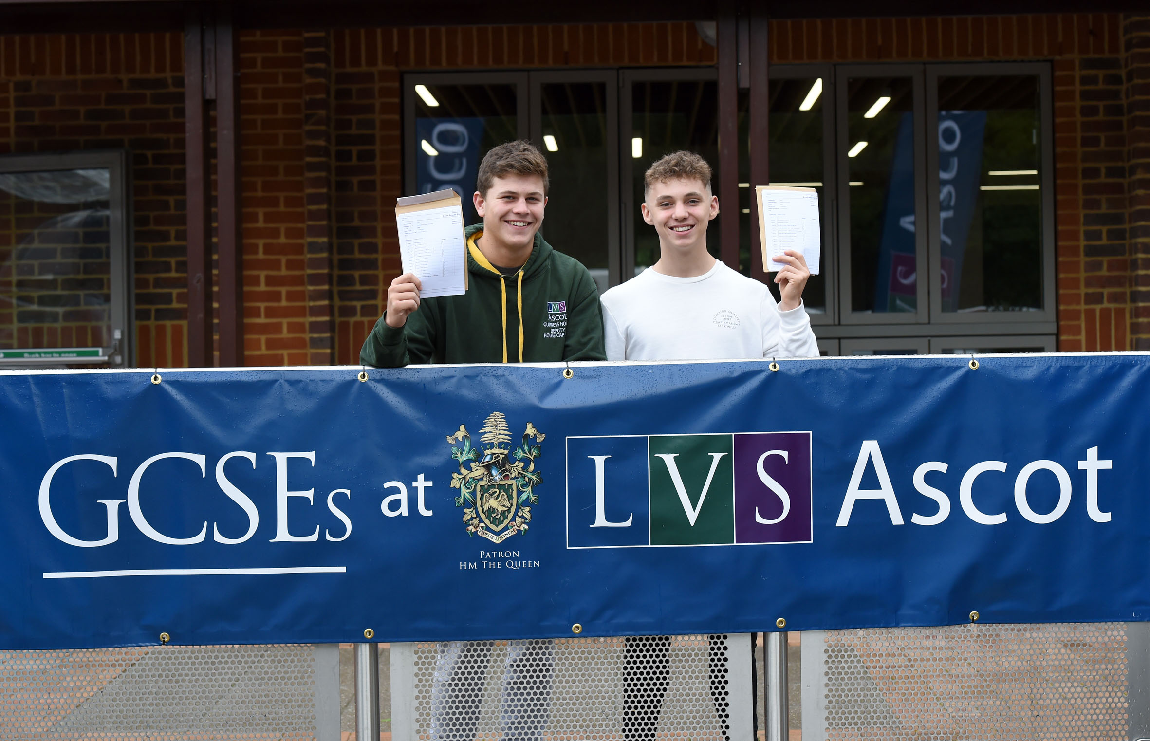 Students holding their GCSE results and smiling