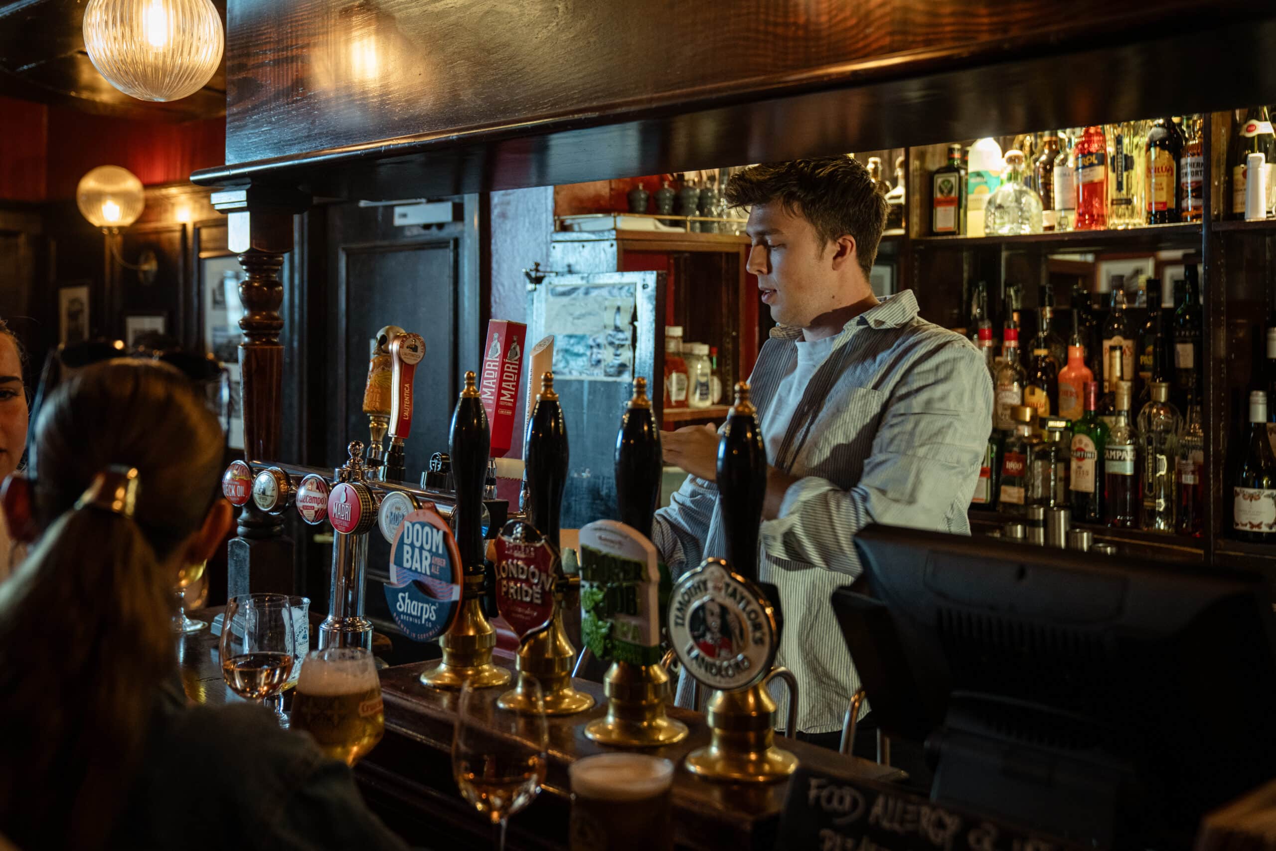 Bartender serving drinks at a busy pub bar, always on shift