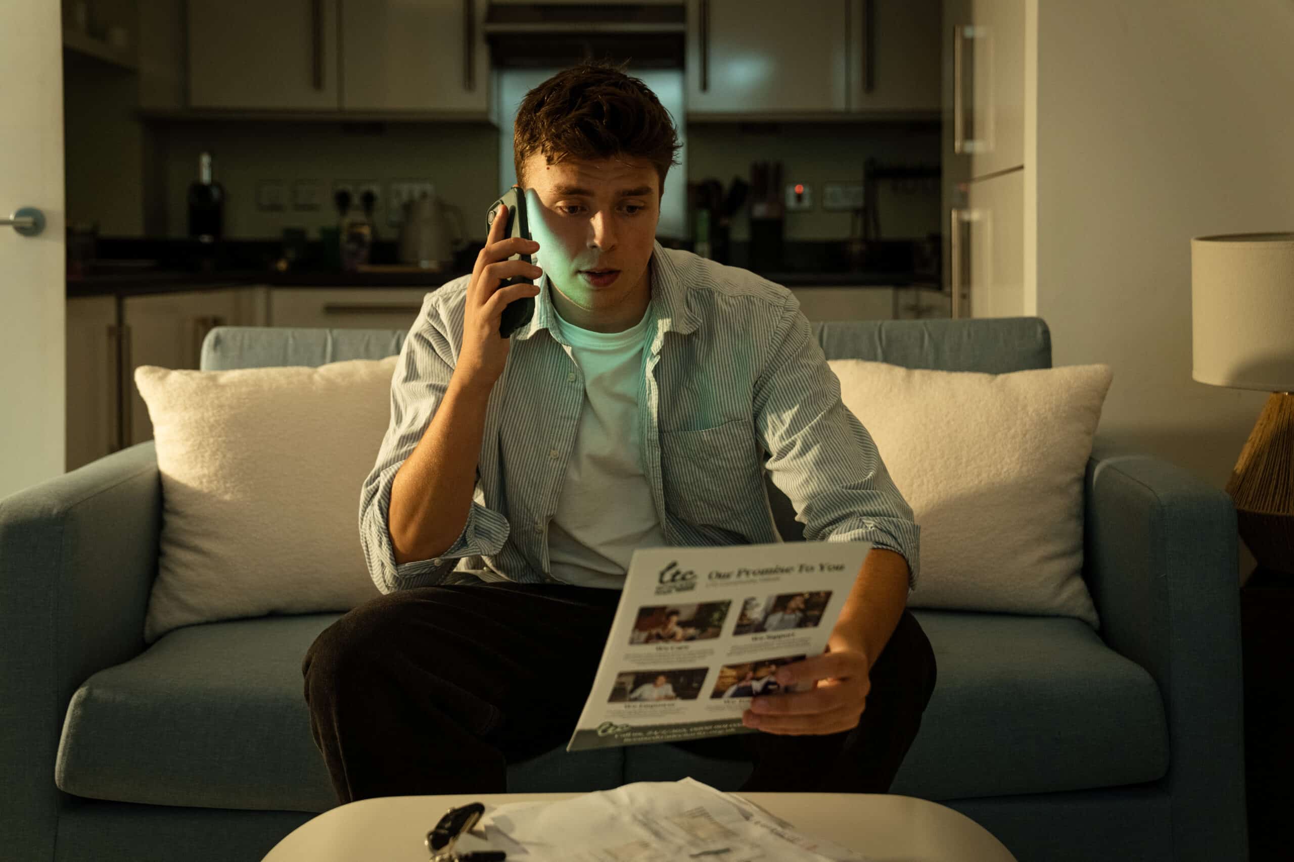 Man on phone reviewing documents on couch, always on shift