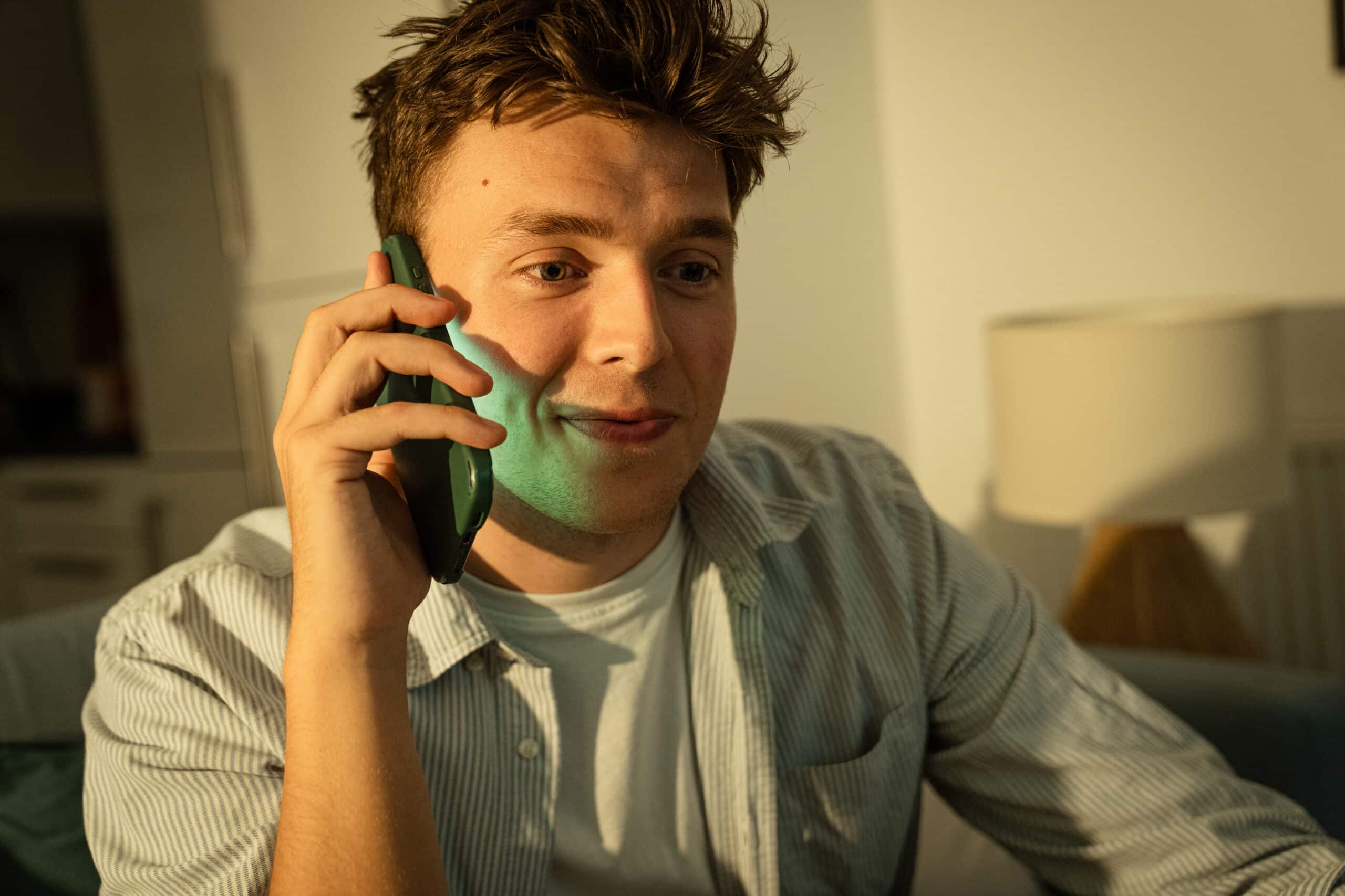 Man on phone, face lit by screen, working late